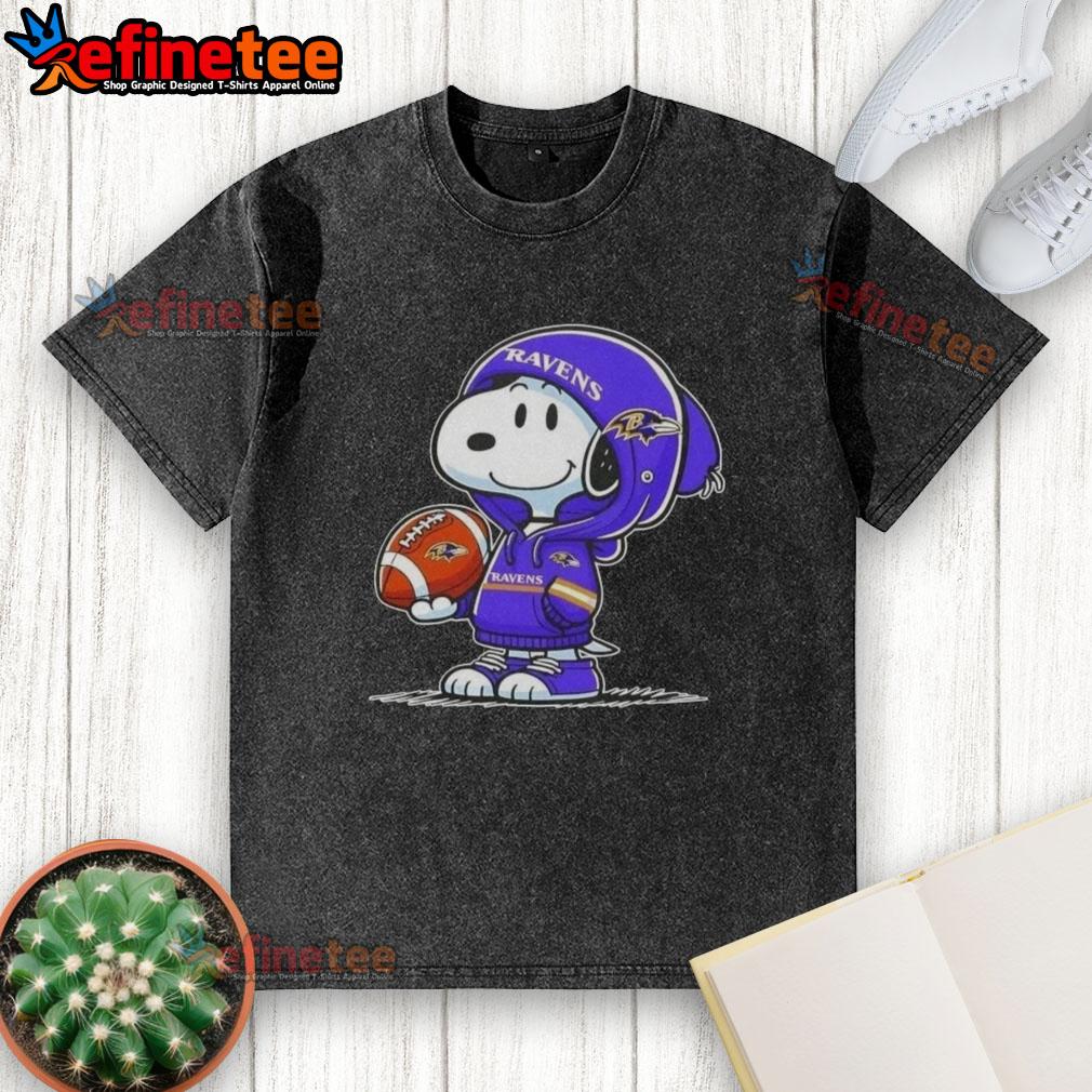 Premium Peanuts Snoopy wearing a Baltimore Ravens hoodie, smiling at fans on a washed t-shirt design.