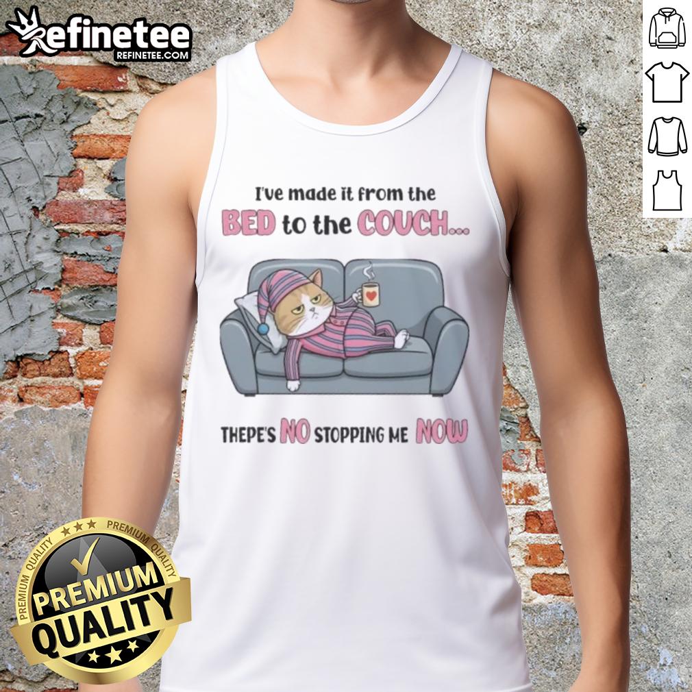 Top tired cat relaxing on a couch after moving from the bed, showcasing its playful spirit in a tank top.