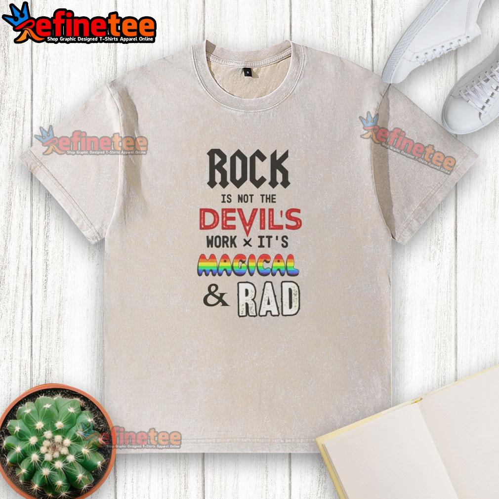 Top Rock Is Not The Devil's Work X Its Magical And Rad washed t-shirt displayed on a wooden background.